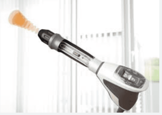A black and silver electric toothbrush with a white brush head on a blurred background.
